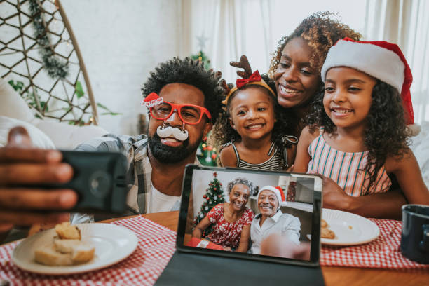 dos generaciones de familia celebrando la navidad en casa y videoconferencia con los abuelos, manteniendo la distancia social - coronavirus fotos fotografías e imágenes de stock