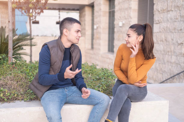 istock Happy young couple sitting on outside, talking, laughing. 1288517986
