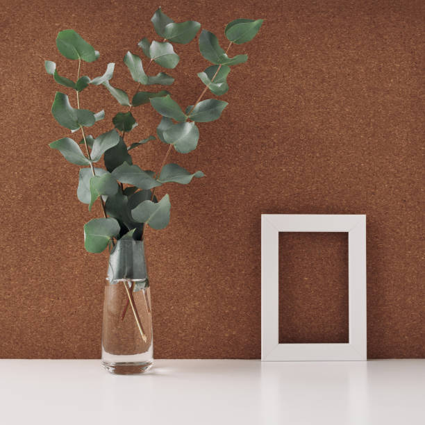 istock Wooden frame and vase with eucalyptus branches, cork background. Mock up, copy space. Folk. 1288520718