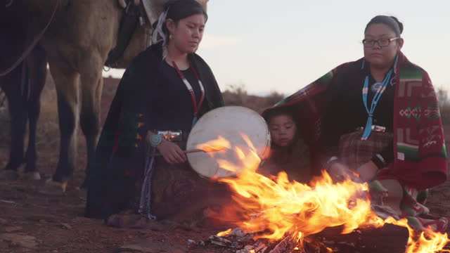 Two Navajo sisters with their little brother around a fire on Monument Valley - Arizona