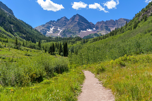 Summer view of a hiking trail in Maroon Creek Valley at base of Maroon Bells. Aspen, Colorado, USA.