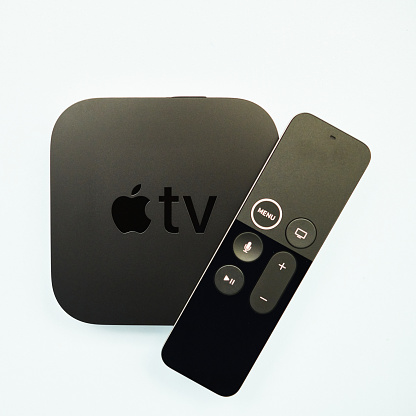 Peyton, Colorado, USA - 28 November 2020: A studio shot of an Apple TV 4K HD box with remote control on a pale blue surface.