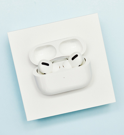 Peyton, Colorado, USA - 28 November 2020: A studio shot of a pair of Apple Air Pods Pro on top of their original packaging. Product shot on a pale blue surface.