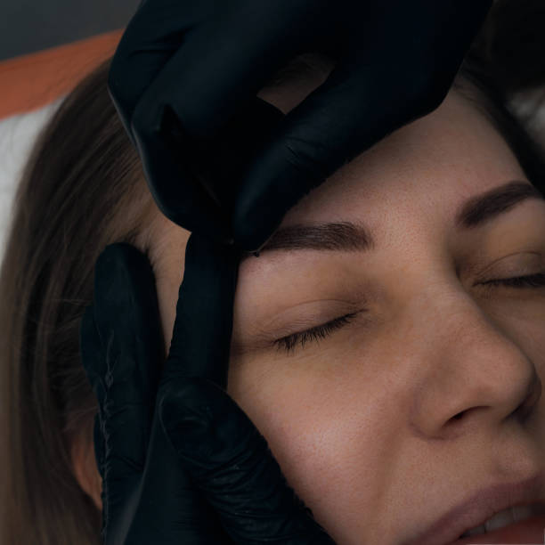 istock Permanent eyebrow makeup procedure. Eyebrow tattooing, process. The use of tools by a master for permanent eyebrow makeup. 1288543744