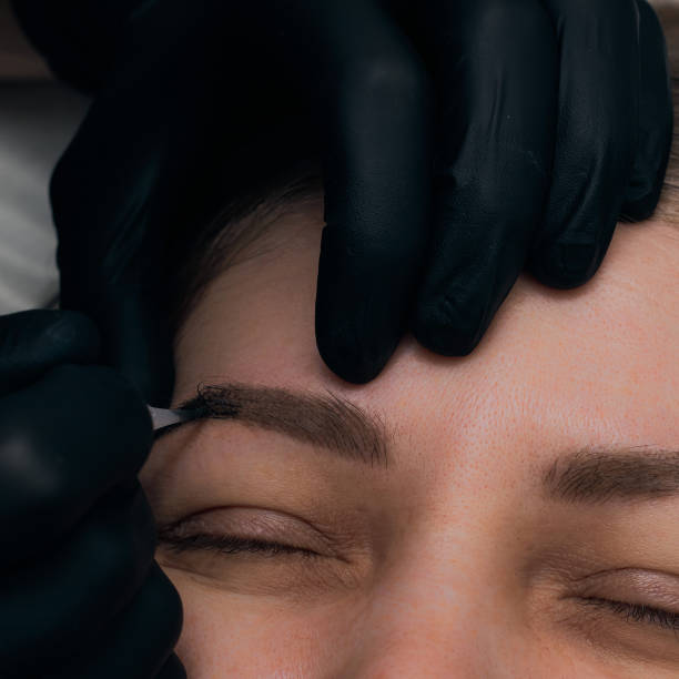 istock Permanent eyebrow makeup procedure. Eyebrow tattooing, process. The use of tools by a master for permanent eyebrow makeup. 1288543745