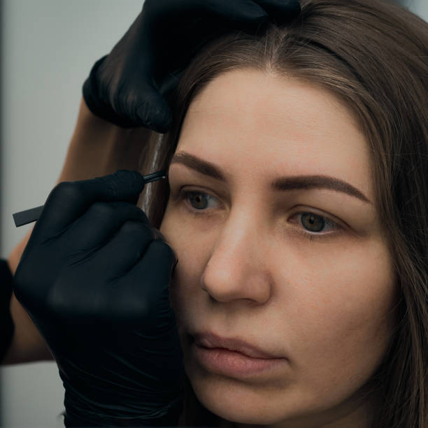 istock Permanent eyebrow makeup procedure. Eyebrow tattooing, process. The use of tools by a master for permanent eyebrow makeup. 1288543788