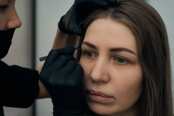 istock Permanent eyebrow makeup procedure. Eyebrow tattooing, process. The use of tools by a master for permanent eyebrow makeup. 1288543791