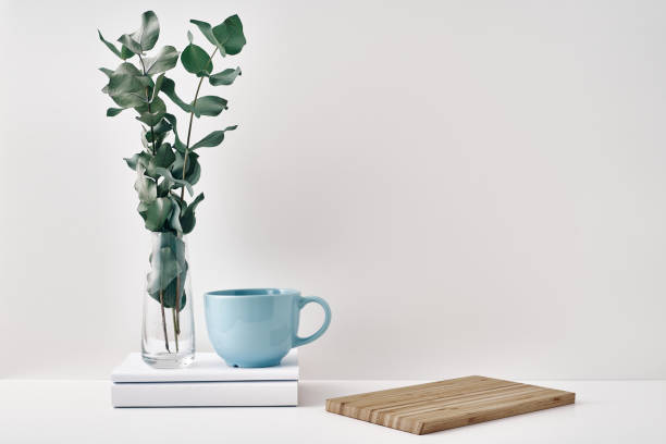 istock A mug, a stack of books, a wooden board and a transparent vase with eucalyptus branches. Eco-friendly materials in interior decor, minimalism. Copy space, mock up. 1288544501
