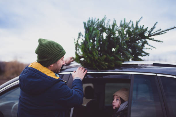 istock Father discussing with his daughter while loading the Christmas tree on top of the car 1288544538