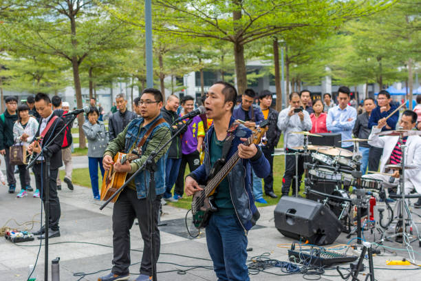 due uomini della band locale di shenzhen che suonano la chitarra e cantano al parco centrale di shenhzhen. - popular music concert outdoors central park people foto e immagini stock