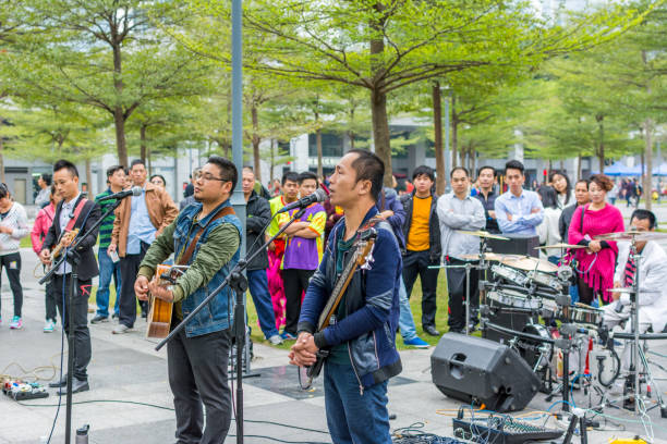 due uomini della band locale di shenzhen che suonano la chitarra e cantano al parco centrale di shenhzhen. - popular music concert outdoors central park people foto e immagini stock