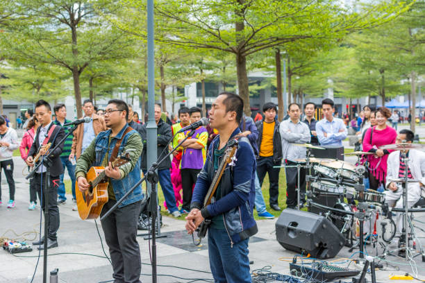 due uomini della band locale di shenzhen che suonano la chitarra e cantano al parco centrale di shenhzhen. - popular music concert outdoors central park people foto e immagini stock