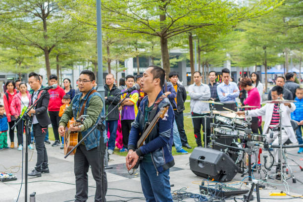 due uomini della band locale di shenzhen che suonano la chitarra e cantano al parco centrale di shenhzhen. - popular music concert outdoors central park people foto e immagini stock