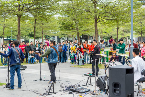 due uomini della band locale di shenzhen che suonano la chitarra e cantano al parco centrale di shenhzhen. - popular music concert outdoors central park people foto e immagini stock