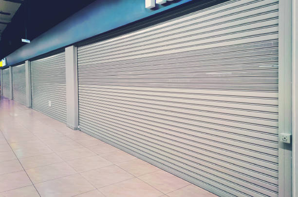 istock shop exterior with closed shutters. Small business problems during coronavirus pandemic covid19. cafe is closed for quarantine due to covid 19 epidemic. shop window is closed by automatic gates. 1288546422