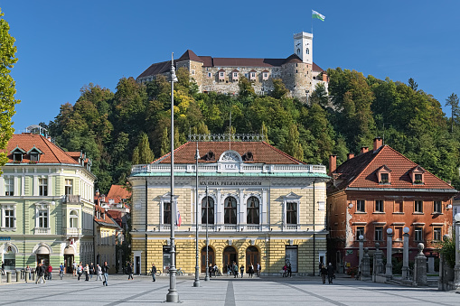 Ljubljana, Slovenia - October 4, 2018: The Slovenian Philharmonic Building on the background of Ljubljana Castle. The building was constructed in 1891 by design of the Austrian architect Adolf Wagner. The castle was founded in the 11th century.