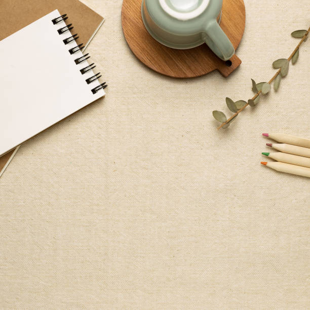 istock Work and study place. Notebooks, mug cup, colored pencils on beige fabric background. flat lay, top view, copy space 1288549480