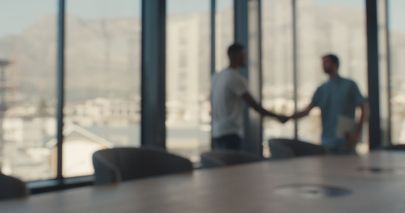 Defocused shot of two businessmen shaking hands in an office