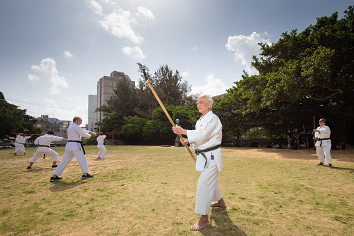 April 01/2018 Sogenji Park in Naha city of Okinawa. Traditional Okinawa Karate practitioners, both young and old train with Bo staff in the outdoors in a park.  \nKarate (空手)is a martial art developed in the in what is now Okinawa, Japan. It was developed from indigenous fighting methods called te (手, literally \