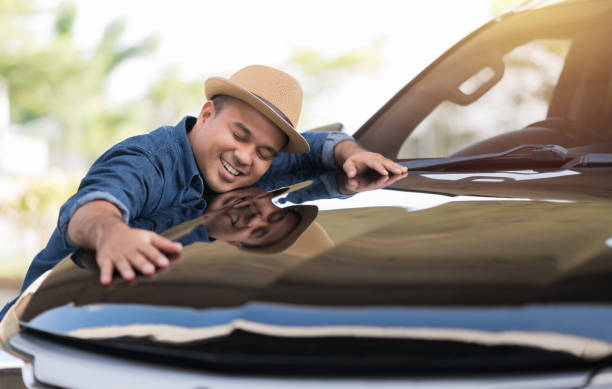 young handsome asian man getting the new car. he hugged his car and was very happy. buy or rent car concept. - cars imagens e fotografias de stock