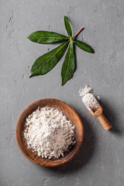 istock Cassava flour in wooden bowl with original leaf on grey background 1288558491