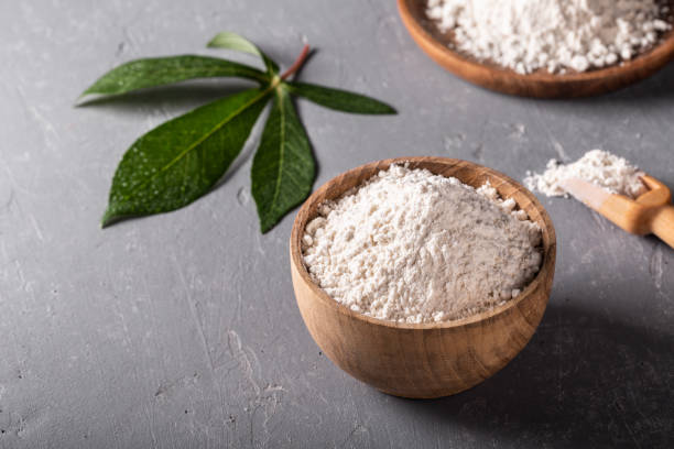istock Cassava flour in wooden bowl with original leaf on grey background 1288558493