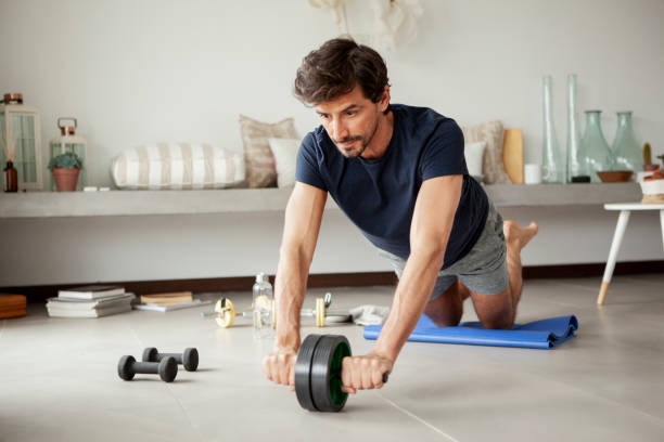 リビングルームで運動する男性 - 腹筋ローラー ストックフォトと画像