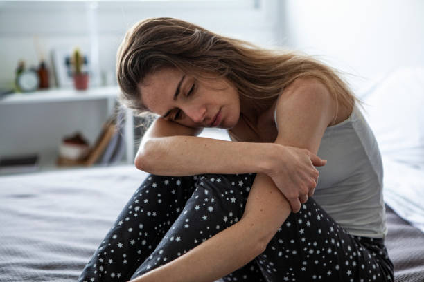 Thoughtful woman sitting in bedroom
