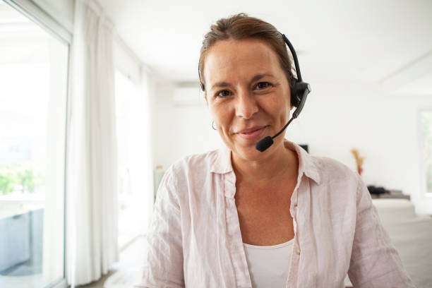 Portrait of woman with headset Portrait of smiling woman with headset having online business meeting at home during COVID-19 pandemic headset stock pictures, royalty-free photos & images