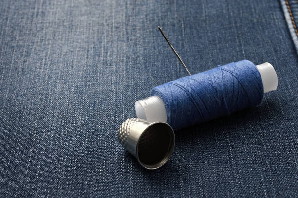 istock a bobbin of thread with a needle and a thimble. on denim background. close-up. 1288563136