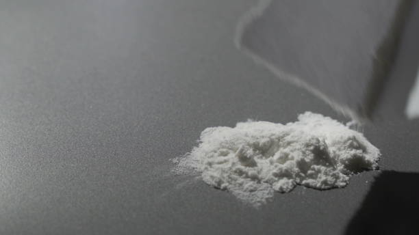 Closeup of a line of cocaine being snorted off a mirror glass surface with a straw. The amphetamines represent the opioid epidemic in America Closeup of a line of cocaine being snorted off a mirror glass surface with a straw. The amphetamines represent the opioid epidemic in America, substance abuse in teens and the the war on drugs. snorting stock pictures, royalty-free photos & images