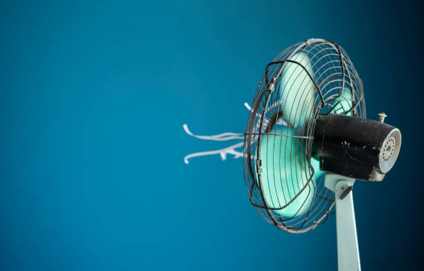 Electric fan with attached streamers Shot of a metal electric fan with white streamers attached against a blue background electric fan stock pictures, royalty-free photos & images