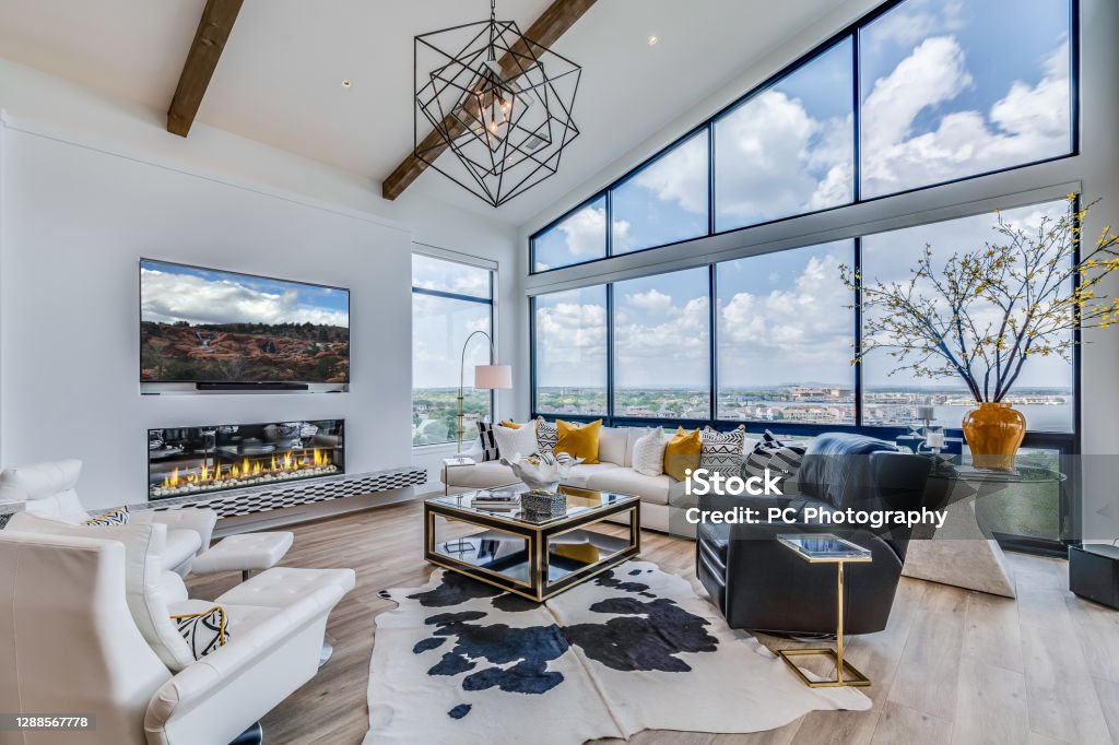 Wood beams rise high above great room Wood floors throughout common area with glass wall and high awning windows Living Room Stock Photo