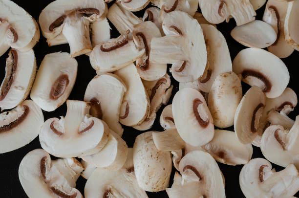 istock Group of raw champignons cut into pieces on black background. 1288569484