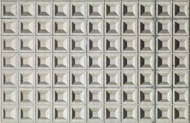 Gray concrete wall decorated with a regular pattern of embossed square shapes. Background and texture.