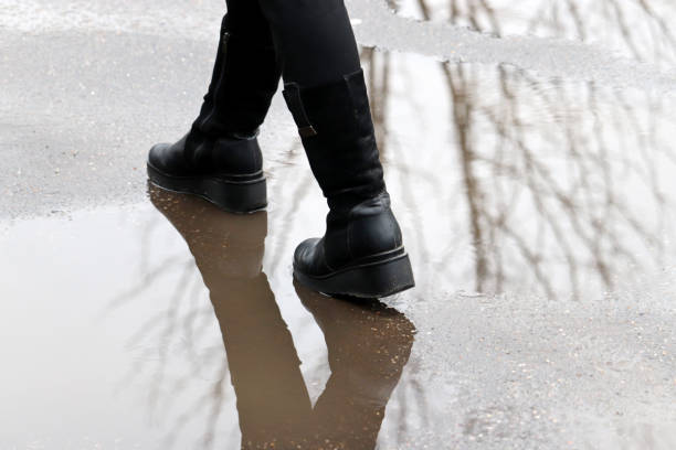 istock Female legs in boots in puddle 1288573496