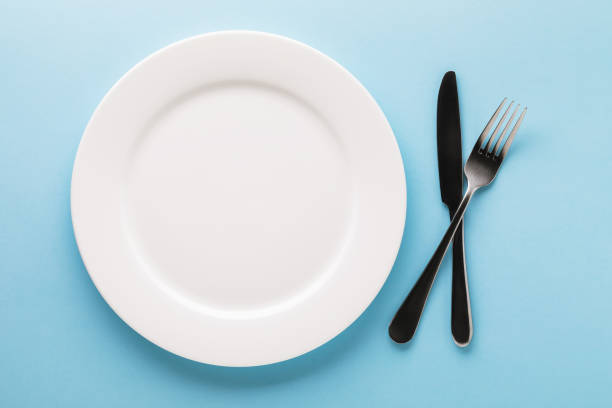 istock White ceramic plate and cutlery on a blue background, top view. Food background 1288576399