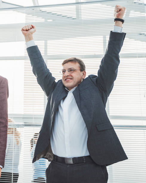 istock happy young businessman standing with hands up 1288581126
