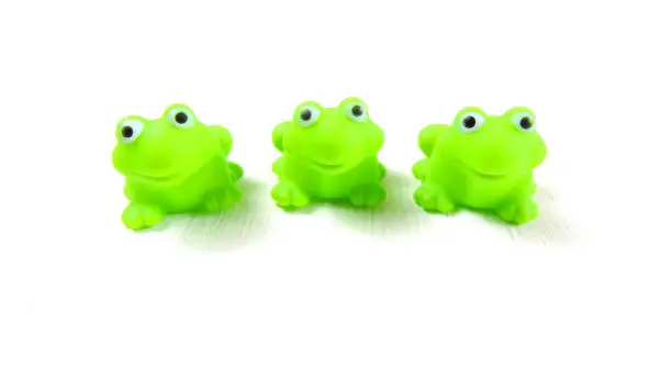 Photo of children's toys three green rubber frog, white background