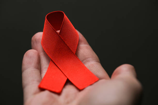 istock AID red ribbon in hand on gray dot 1288585190