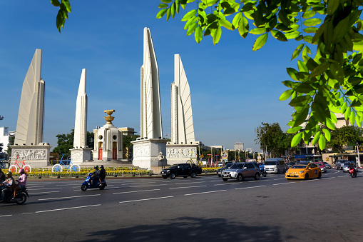 Bangkok, Thailand - December 12, 2018: Busy street of Bangkok downtown with Democracy Monument in sunny day. The Democracy Monument is a public monument in the city center of Bangkok, capital of Thailand.