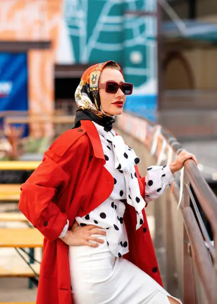 woman in red coat and sunglassess walking around  the citycentre after shopping