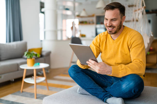 istock Happy man relaxing on sofa with digital tablet 1288587313