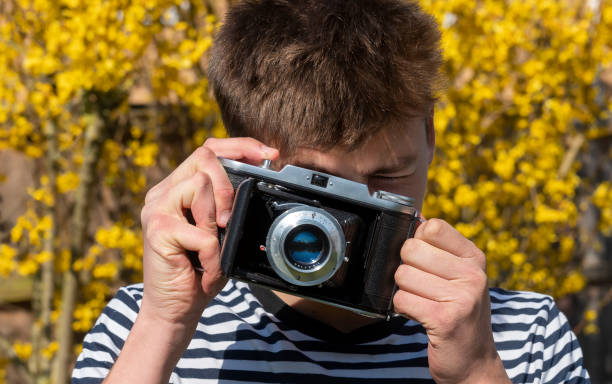istock Young man in a garden with a vintage medium format film camera 1288591275