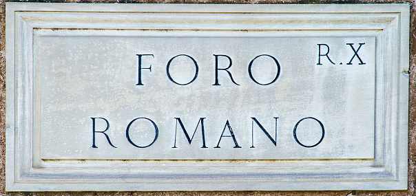 The typical travertine marble plaque with an indication of a street or a square in the historic center of Rome. In the picture: the Roman Forum area indication. Image in High Definition format.