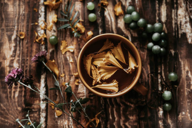 herbal tea. herbal tea in an orange mug on a wooden table. berries, herbs, flowers and tea on a brown wooden table. summer still life with herbs on the kitchen table