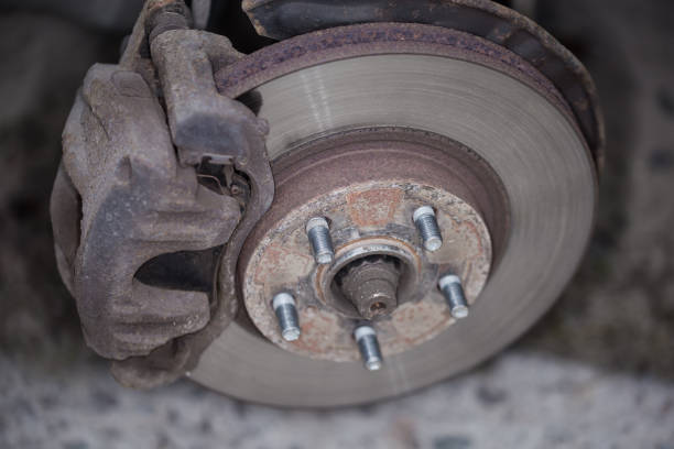Front assembly of ventilated disc brake and wheel hub on an used car, view with removed wheel close-up in selective focus