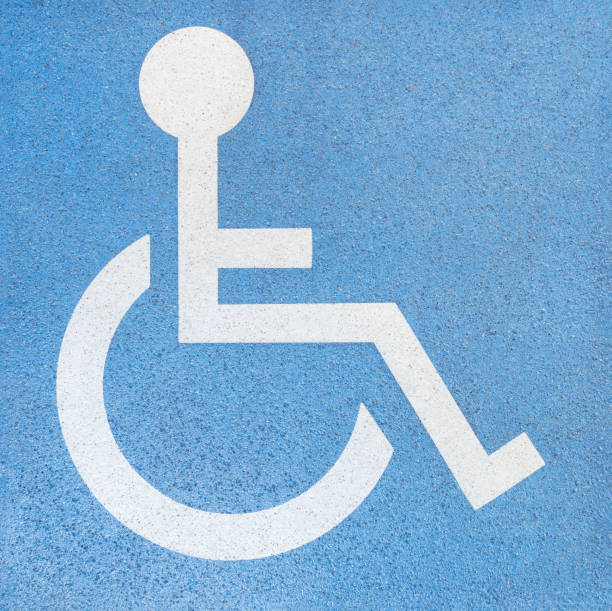 istock Wheelchair user - white sign on blue concrete slab 1288594622