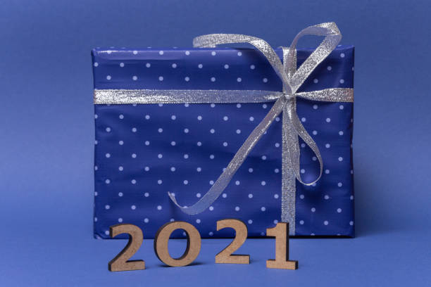 istock Box with gift in wrapped in blue paper with polka dots with silver bow on blue background. Inscription 2021. Present for Christmas, new year, valentine day or anniversary 1288596734