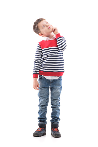 Smart little boy thinking and having idea looking up with finger on cheek. Full body portrait isolated on white background.